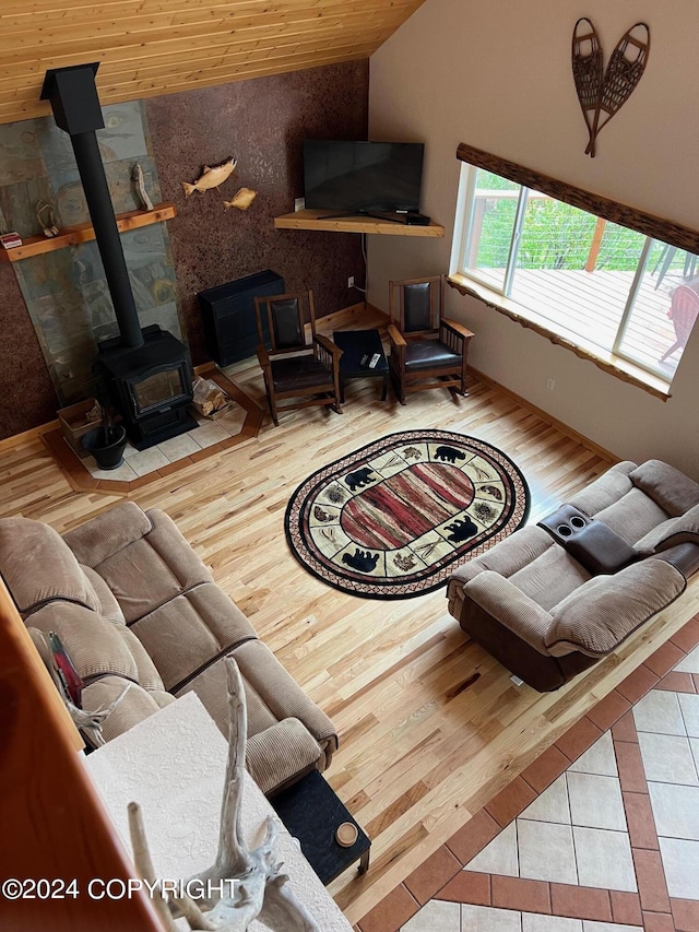 living area featuring vaulted ceiling, wood ceiling, wood finished floors, and a wood stove