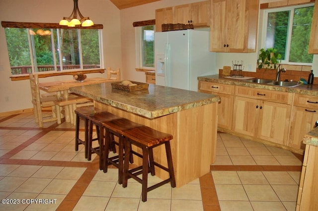 kitchen with light tile patterned floors, white fridge with ice dispenser, a sink, and light brown cabinets