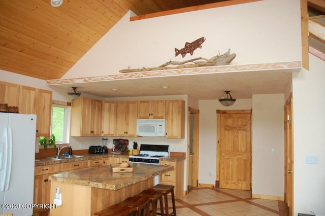 kitchen with white appliances, a kitchen island, a breakfast bar area, light brown cabinets, and a sink