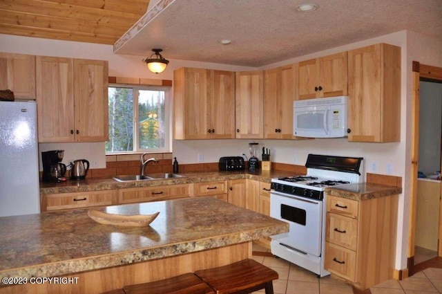 kitchen featuring white appliances, a sink, and light brown cabinetry