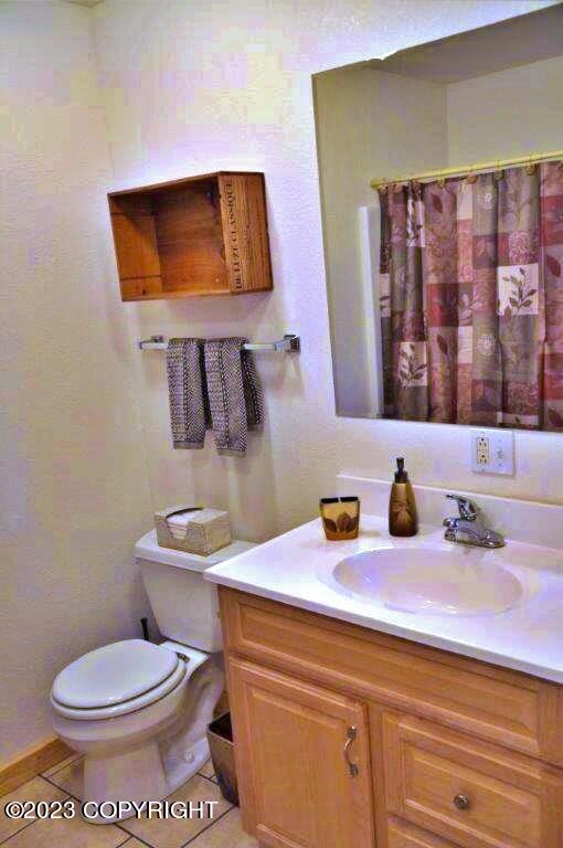 full bathroom featuring toilet, vanity, a shower with shower curtain, and tile patterned floors