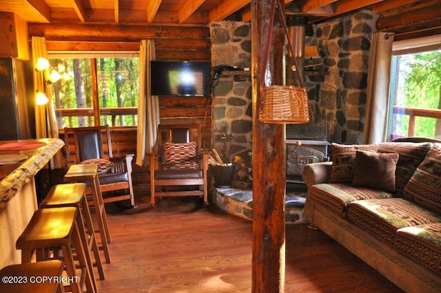 interior space featuring beam ceiling, log walls, and wood finished floors