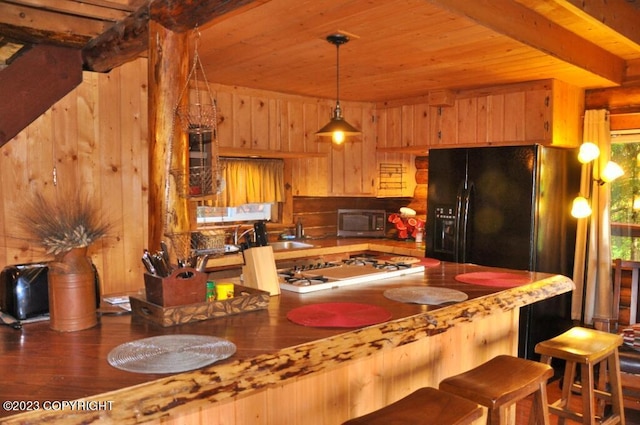 kitchen with white cooktop, stainless steel microwave, beam ceiling, and wooden walls