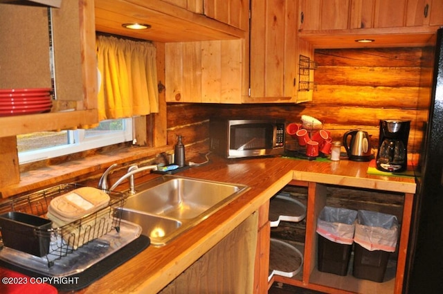 kitchen featuring stainless steel microwave, wooden counters, and log walls