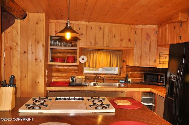 kitchen with white gas cooktop, a sink, tile counters, black refrigerator with ice dispenser, and stainless steel microwave