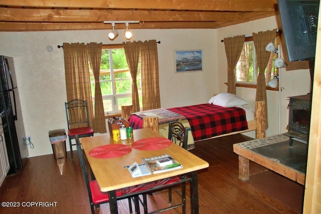 bedroom with freestanding refrigerator, beamed ceiling, and wood finished floors