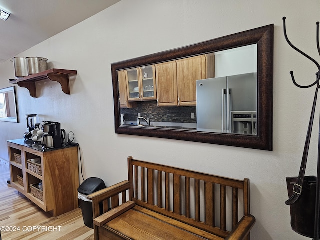 kitchen with open shelves, decorative backsplash, glass insert cabinets, light wood-type flooring, and stainless steel fridge