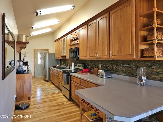 kitchen featuring light wood-style floors, stainless steel appliances, a sink, and brown cabinetry