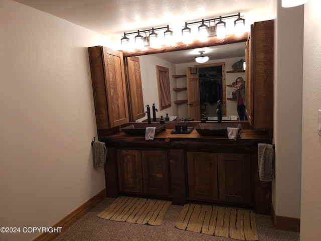 bathroom with rail lighting, a sink, baseboards, and double vanity