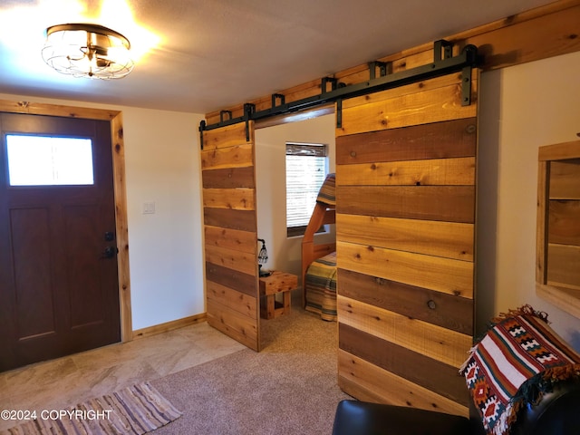 entryway featuring light carpet, a barn door, and baseboards