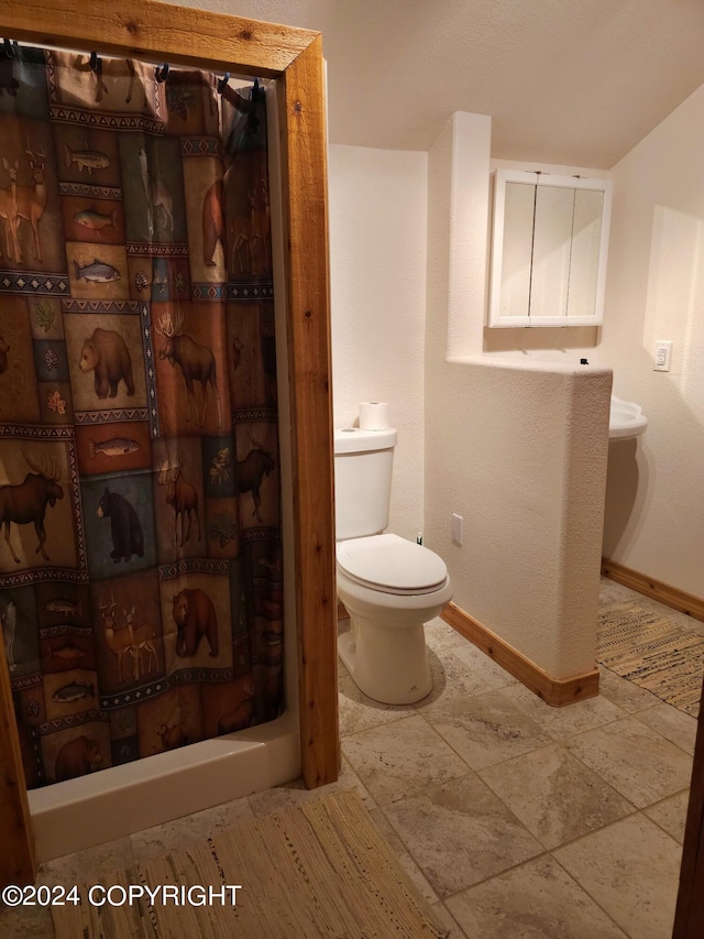 bathroom with toilet, a shower with curtain, and baseboards