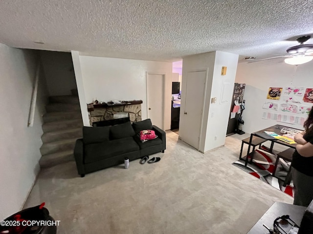 living area featuring stairs, a textured ceiling, a fireplace, and light carpet