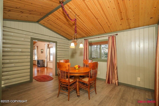 dining room with lofted ceiling, wood finished floors, wooden ceiling, log walls, and baseboards