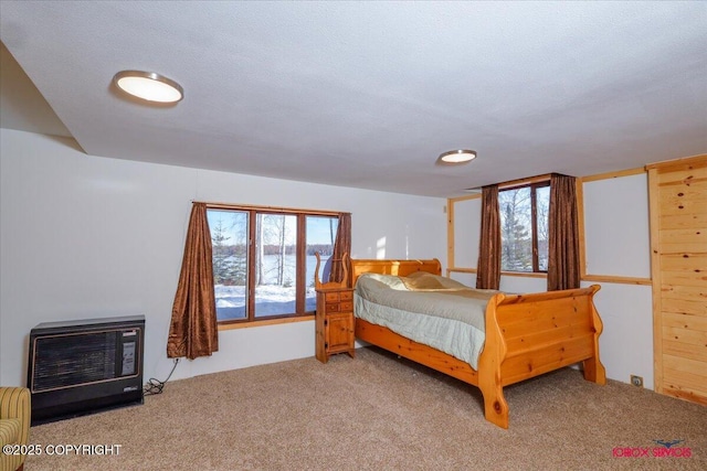 bedroom featuring multiple windows, heating unit, and light carpet