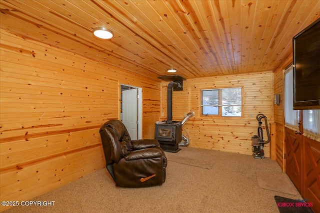 living area with carpet flooring, wood walls, wood ceiling, and a wood stove