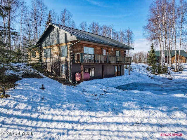 view of front of house featuring a wooden deck, log siding, stucco siding, metal roof, and a standing seam roof