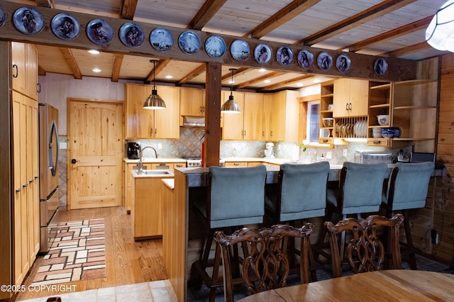 kitchen with beam ceiling, tasteful backsplash, stainless steel fridge, and a sink