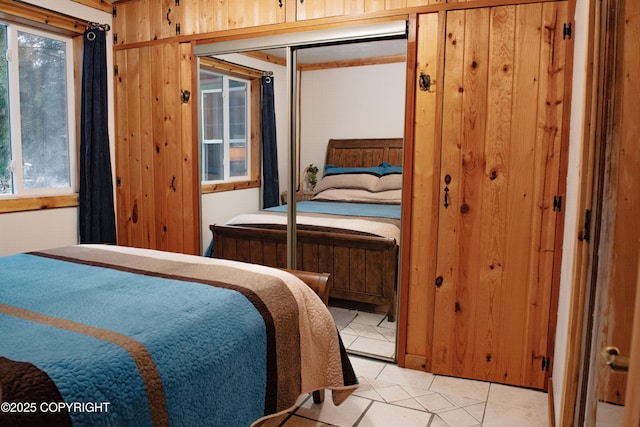 bedroom with wooden walls, multiple windows, and light tile patterned flooring