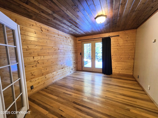 spare room with wooden walls, french doors, wood ceiling, and wood finished floors