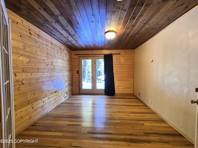 empty room with wood finished floors, wood ceiling, wood walls, and french doors