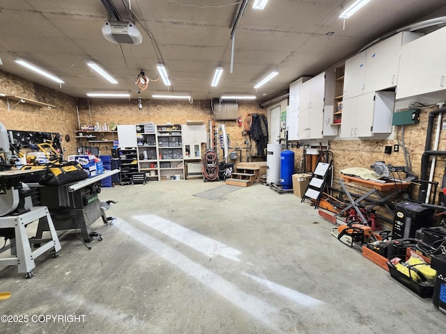 garage featuring water heater, a workshop area, and a garage door opener