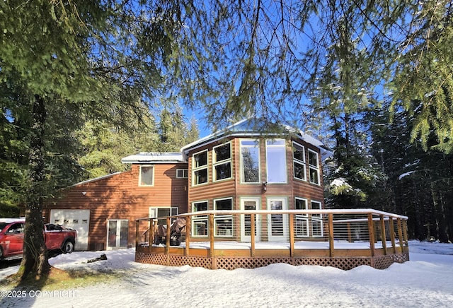 view of front of home with a wooden deck, an attached garage, and faux log siding