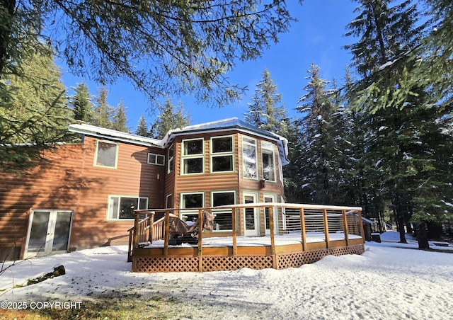 snow covered rear of property with log veneer siding and a deck