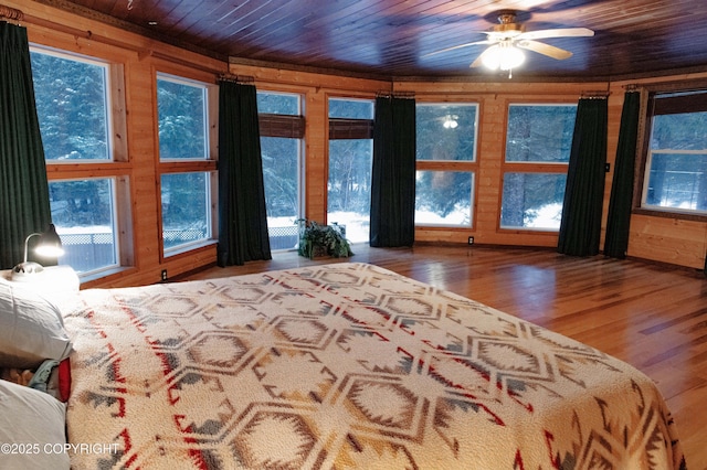 bedroom with multiple windows, wood ceiling, wood finished floors, and wood walls