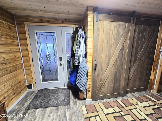 foyer entrance featuring wood walls, wood ceiling, a barn door, and wood finished floors