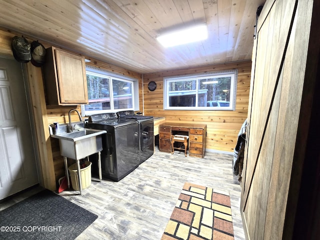 laundry room with wood ceiling, separate washer and dryer, wood walls, and light wood-style flooring