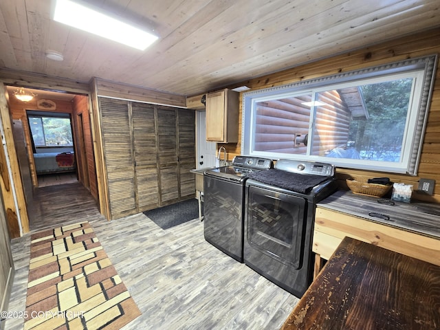 laundry room with cabinet space, wood walls, light wood finished floors, wood ceiling, and washing machine and clothes dryer