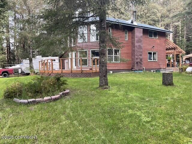 back of property featuring a lawn, a deck, and faux log siding