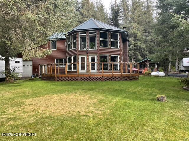 rear view of property featuring a yard, metal roof, and a deck