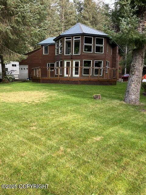 back of property with metal roof and a lawn