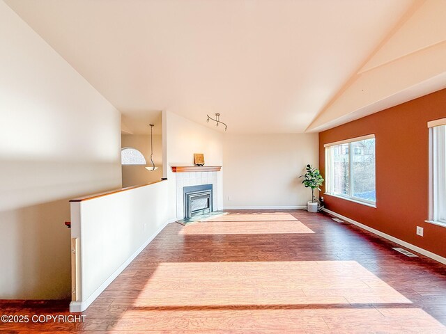 unfurnished living room with visible vents, baseboards, lofted ceiling, and wood finished floors