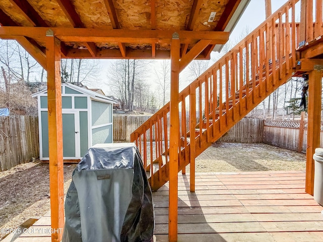 wooden terrace with an outbuilding, a grill, a storage unit, and a fenced backyard