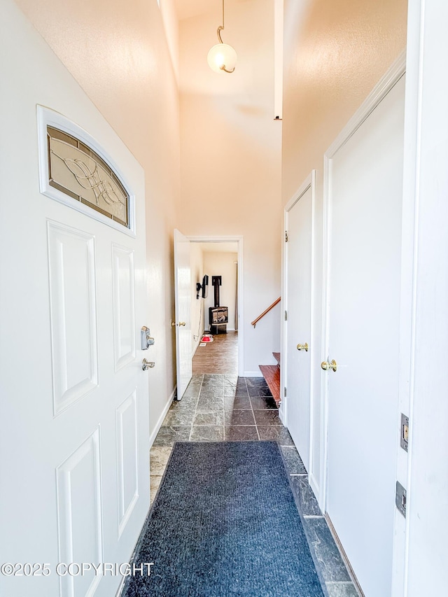 hall featuring stairs, a high ceiling, baseboards, and stone finish flooring