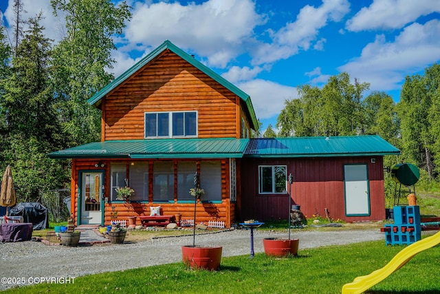 rear view of house with a playground, a yard, and metal roof