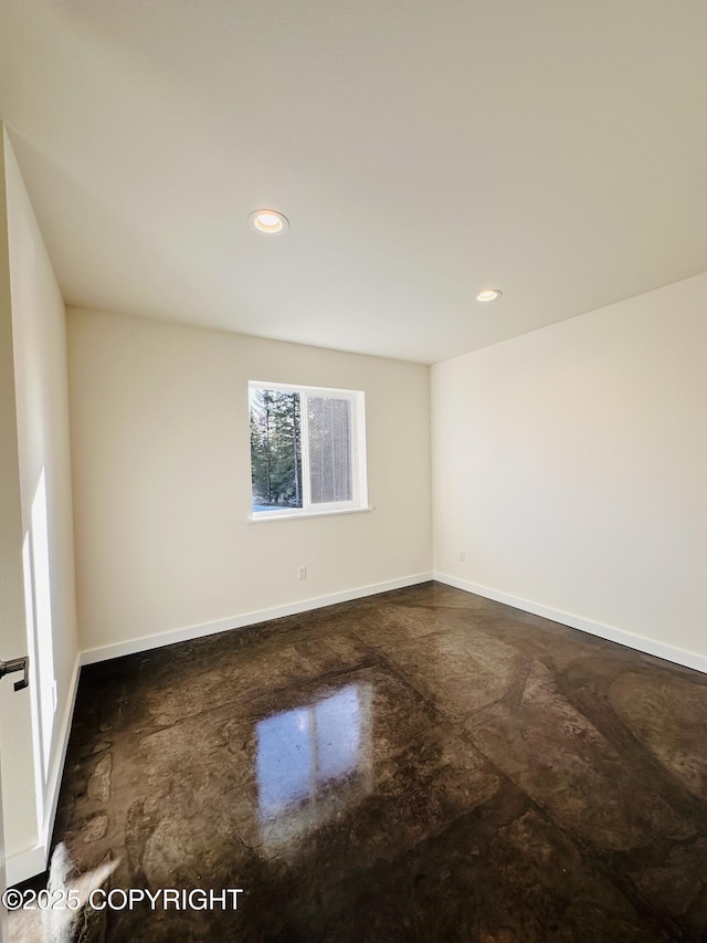 spare room featuring recessed lighting, finished concrete flooring, and baseboards