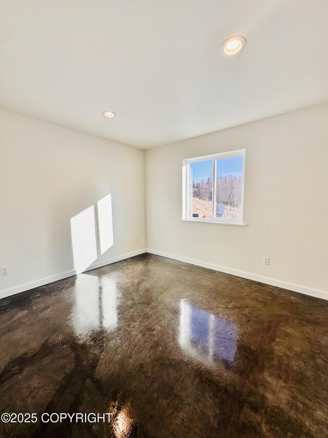 empty room featuring recessed lighting, baseboards, and finished concrete floors