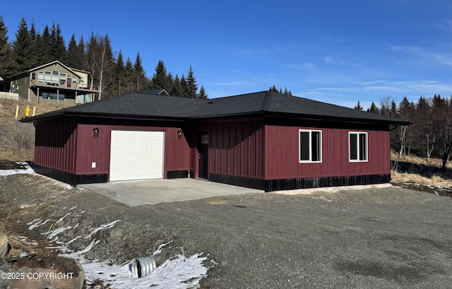 view of front of property featuring driveway, a shingled roof, and a garage