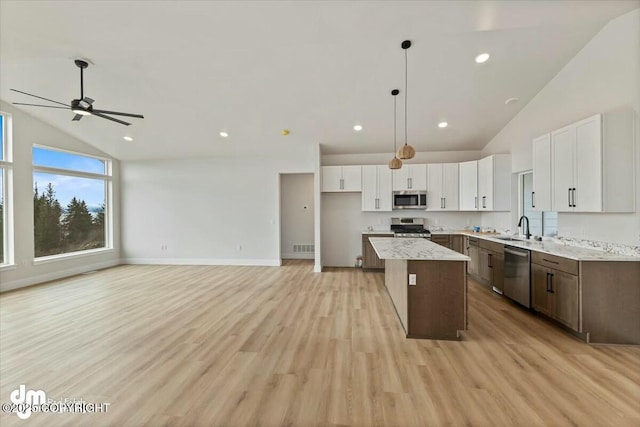 kitchen with a sink, stainless steel appliances, a kitchen island, and white cabinets