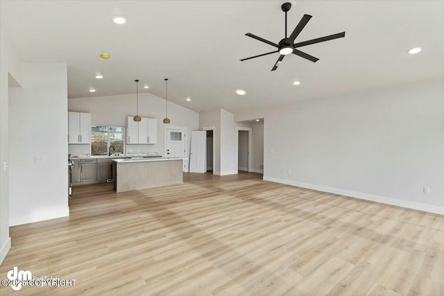 unfurnished living room with ceiling fan, light wood-type flooring, lofted ceiling, and a sink