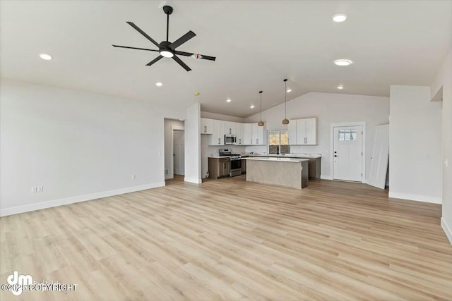 unfurnished living room with a ceiling fan, vaulted ceiling, light wood-style floors, and baseboards