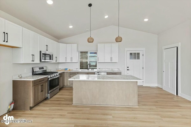 kitchen featuring light wood finished floors, a center island, appliances with stainless steel finishes, white cabinets, and a sink