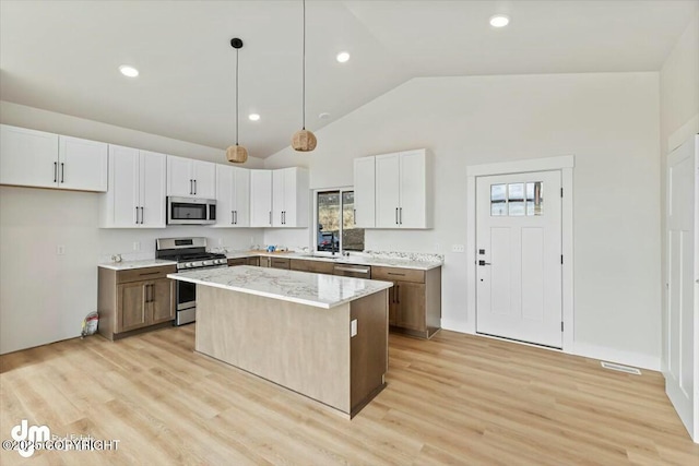 kitchen featuring light wood-style flooring, appliances with stainless steel finishes, a center island, and pendant lighting