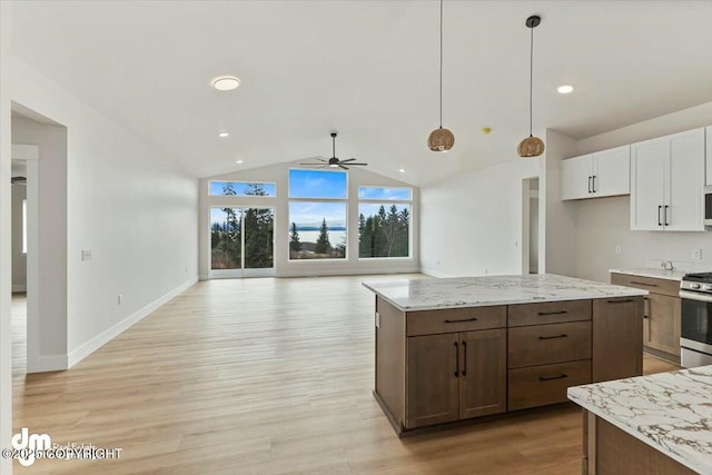 kitchen featuring light wood-type flooring, open floor plan, white cabinets, decorative light fixtures, and stainless steel gas stove