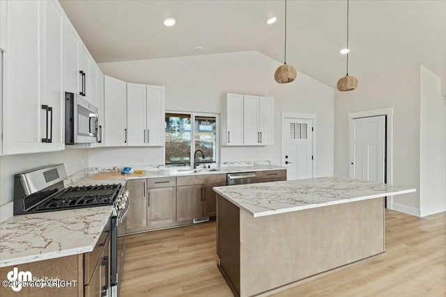 kitchen with light stone countertops, light wood-style floors, appliances with stainless steel finishes, and a sink