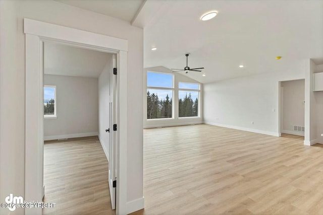 empty room featuring a wealth of natural light, light wood-type flooring, ceiling fan, and vaulted ceiling