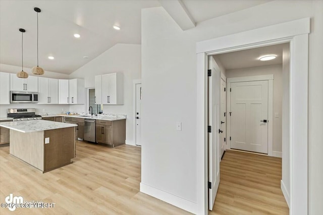 kitchen with light wood-style flooring, appliances with stainless steel finishes, a kitchen island, and a sink